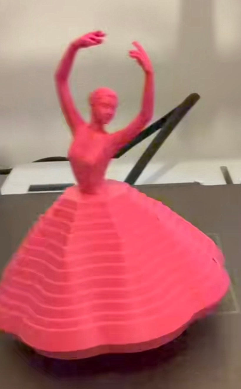 Pink 3D printed ballerina fidget with layered skirt on a purple stand
