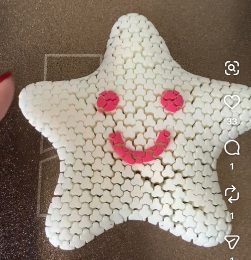 White articulated star sensory fidget with a pink smiling face