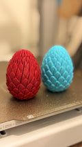 Red and turquoise 3D printed dragon eggs with a raised scale pattern