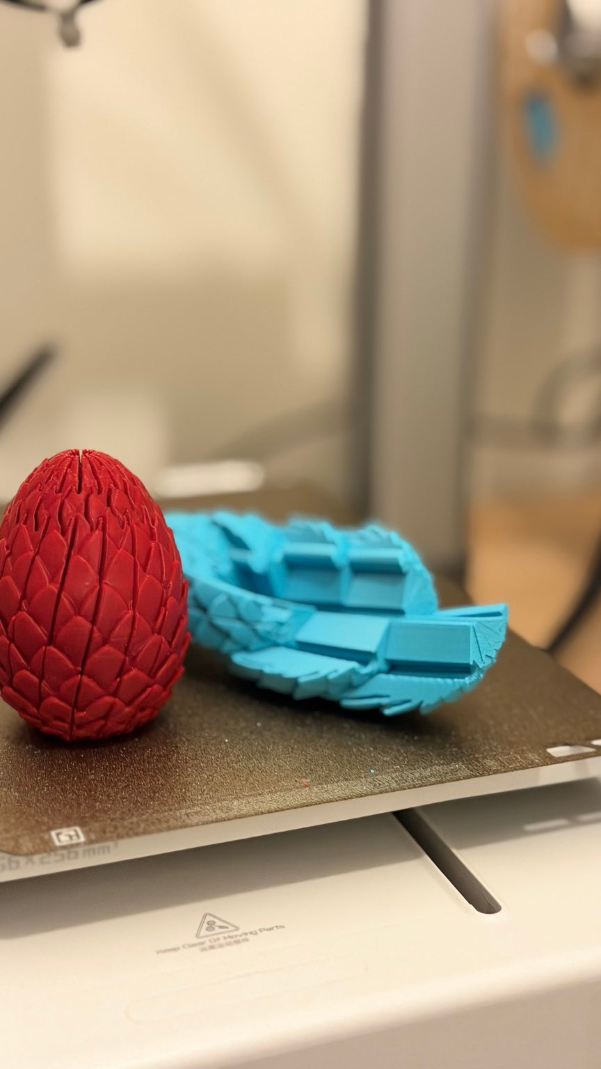 Red dragon egg beside an unfolded turquoise dragon egg showing its connected sections