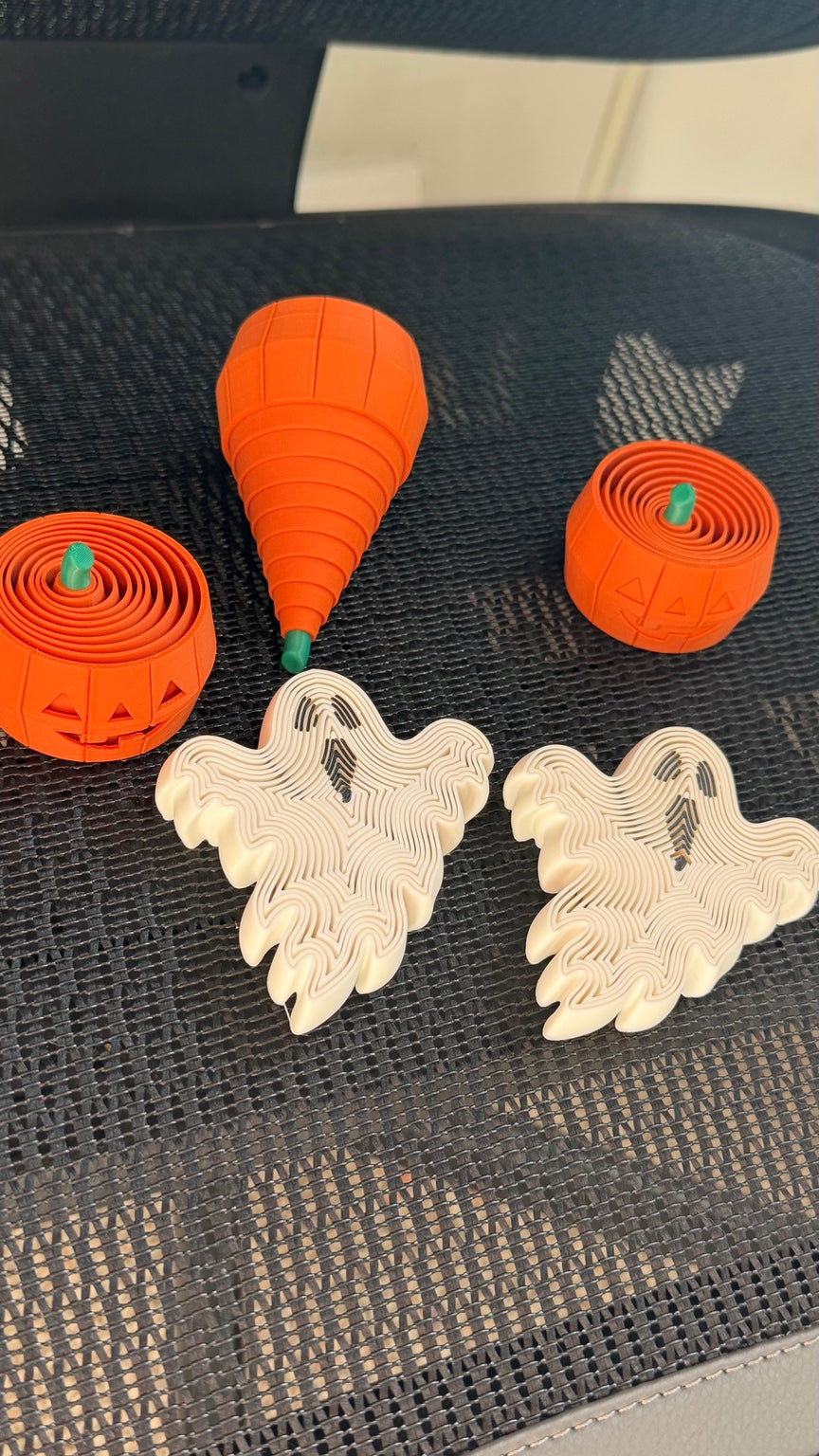 White ghost fidgets and orange pumpkin fidgets shown in extended and collapsed positions