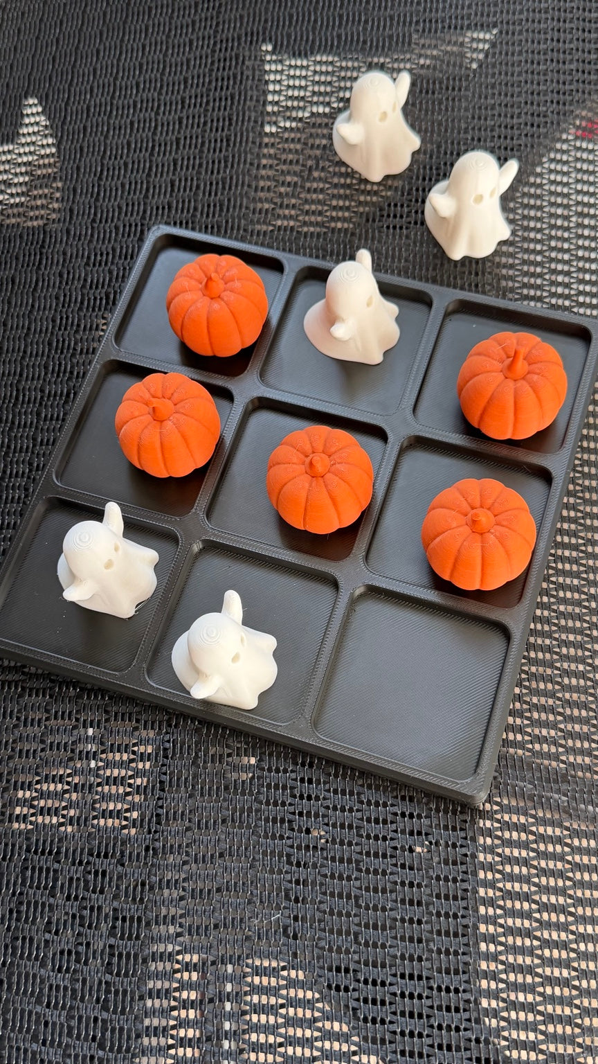 Halloween tic tac toe set with ghost and pumpkin pieces arranged on and beside the board