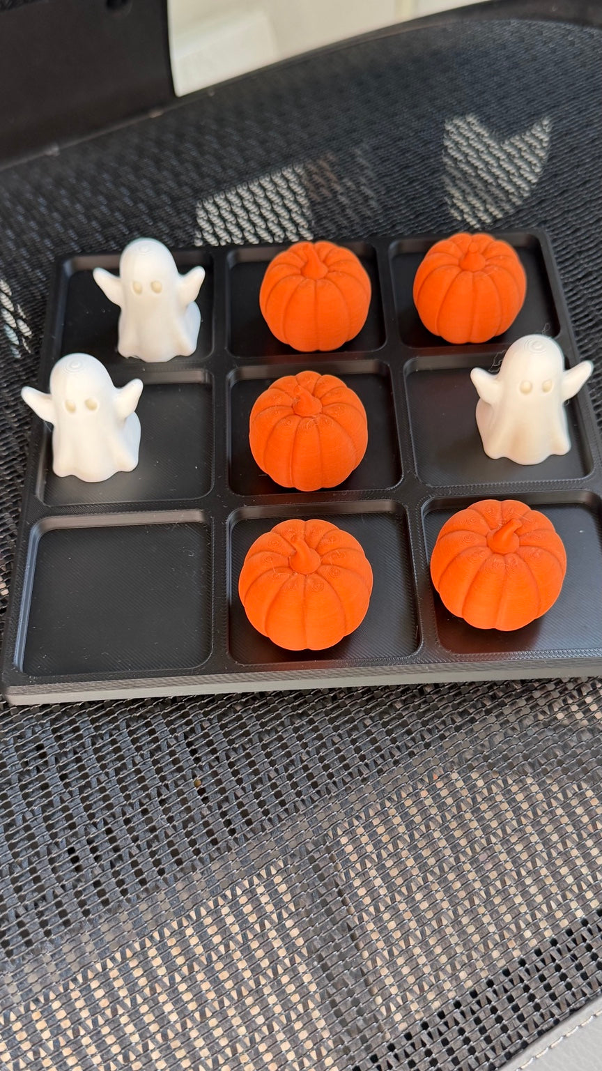 Black tic tac toe board with orange pumpkin and white ghost playing pieces
