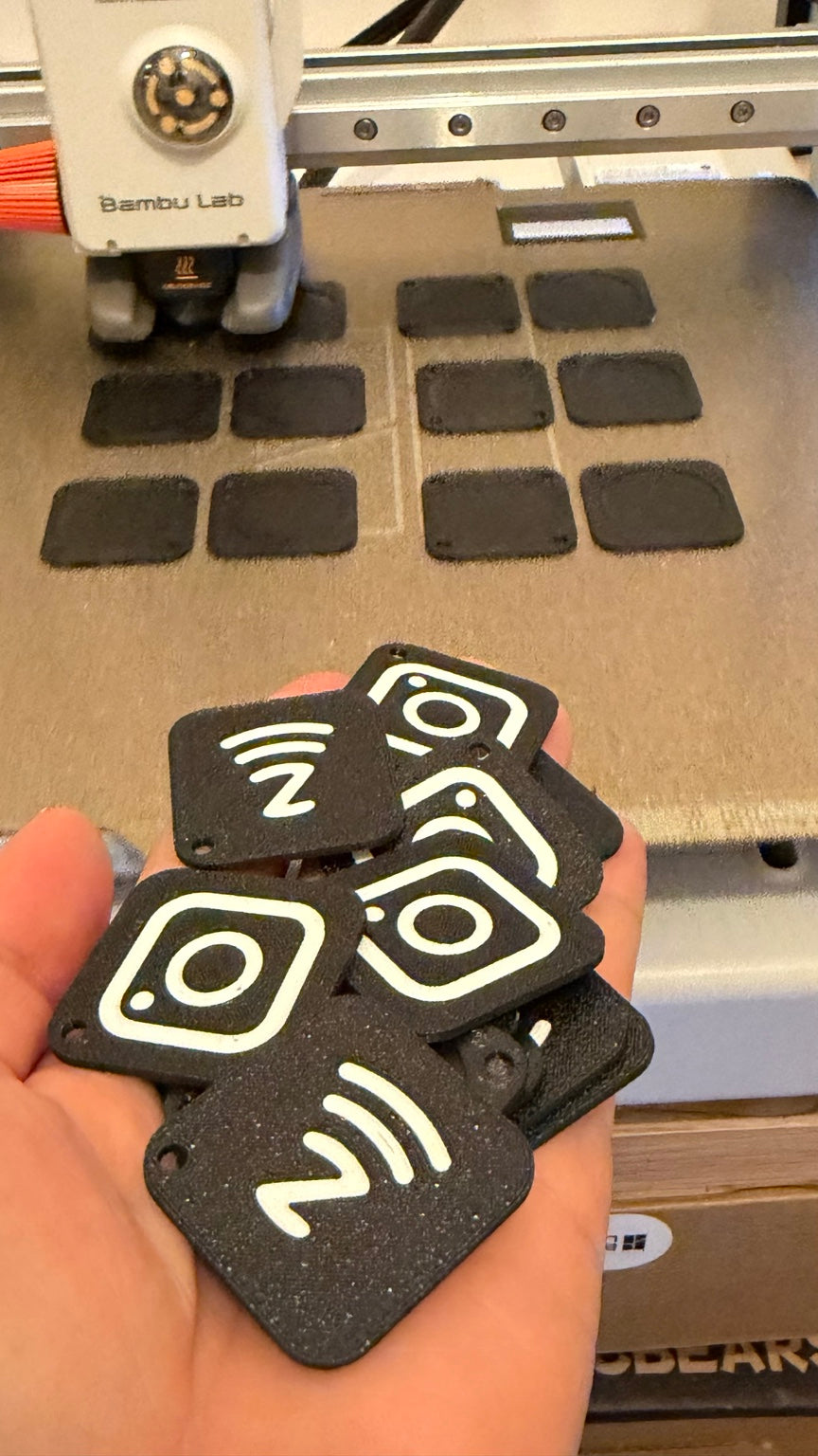 3D printed Instagram and NFC tags with black backgrounds and light lettering