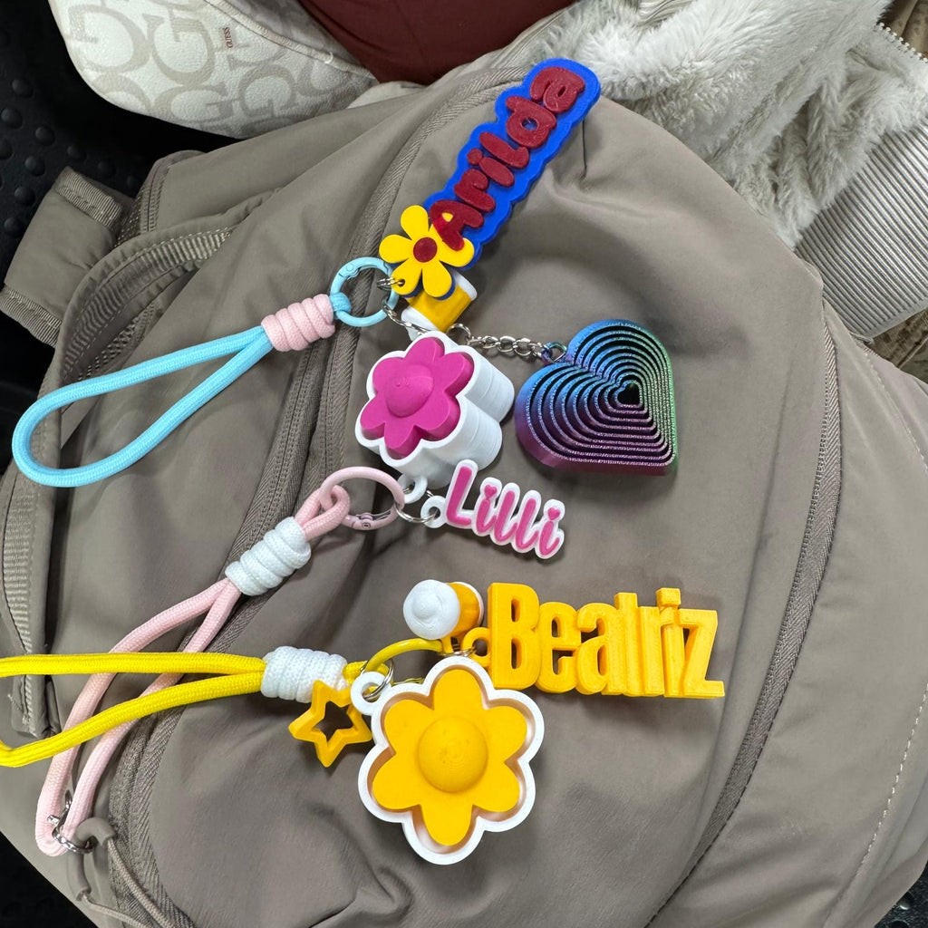 Examples of personalised 3D printed name keyrings in different colours with wrist straps and charms